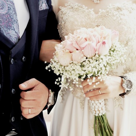 Mariés bras dessus bras dessous, la mariée tenant un bouquet de roses roses et de gypsophile