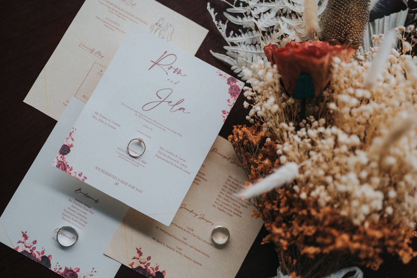 Texte de faire-part de mariage posé avec des alliances et un bouquet séché